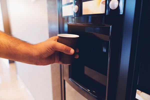 Main se servant un café à une machine automatique - Duval Distribution