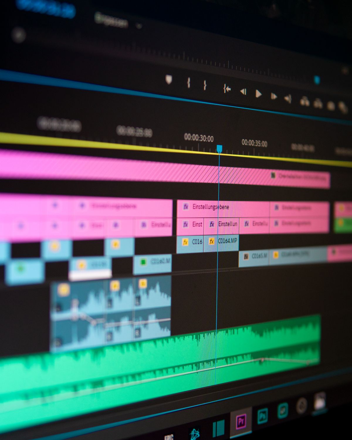 Gros plan sur une timeline de montage : pistes vidéo roses et bleues, piste audio verte et curseur de lecture.